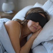 Woman asleep on her side wearing The Eclipse sleep mask in Midnight Black