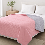 The Breeze cool-touch summer blanket in Blush Rose on a made bed