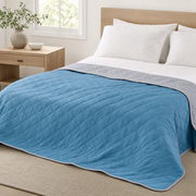 The Breeze cool-touch summer blanket in Harbor Blue on a made bed, grey reverse showing
